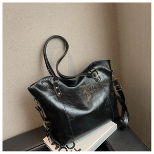 Detail of a large black leather tote bag with dual straps and adjustable shoulder strap