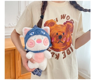Detail shot of a cute white cat plush backpack wearing a blue shark hat with soft fur texture