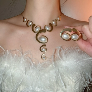 Close-up of elegant gold metal tassel necklace and pearl earrings on model