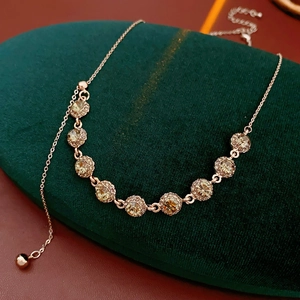 Macro view of rose gold floral necklace with champagne crystals on green velvet