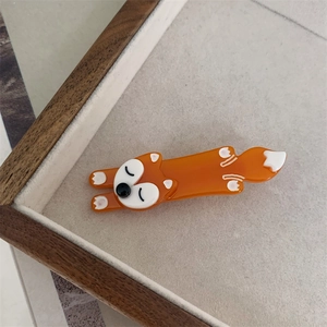 Close-up of orange acetate fox hair clip placed in a wooden tray for styling hair