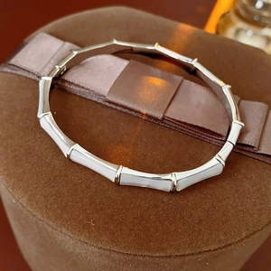 Detailed close-up of bamboo-style silver bracelet with white mother of pearl inlays
