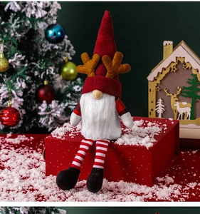 Christmas gnome doll with antlers sitting on a red gift box near a festive tree