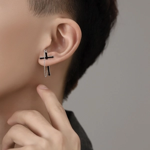 Detail of silver chain earring with black enamel cross pendant worn on ear