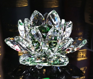Macro shot of faceted clear and green crystal lotus flower with reflections on black surface