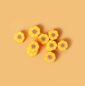 Vue de dessus des perles de tournesol en pâte polymère jaune pour bijoux DIY sur fond orange