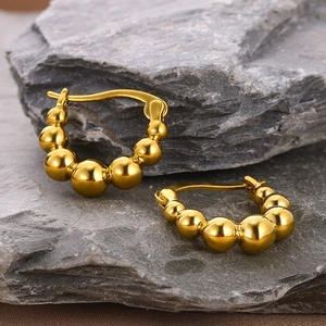 Macro shot of 18k gold plated beaded hoop earrings resting on grey volcanic rock