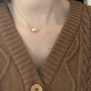 Minimalist 925 sterling silver gold-plated necklace with a bean pendant on a knit sweater
