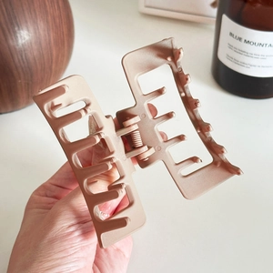 Matte dusty pink square hair claw clip for elegant updo styles held in hand