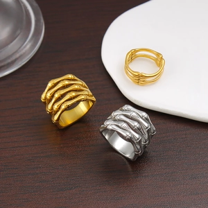 Unique 18K gold and silver skeleton hand bone rings displayed on a textured wooden background