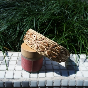 Detail of woven raffia headband with floral patterns on a white mosaic surface