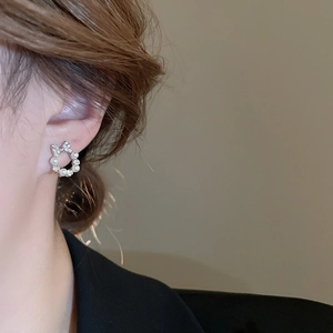Close-up of bow knot earrings with cubic zirconia and pearls shown on a model