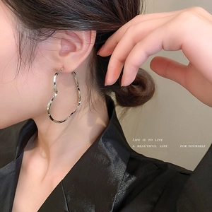 Silver heart-shaped hoop earrings with liquid metal design on a female model