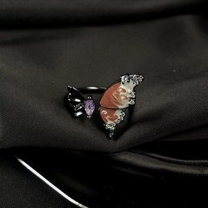 Detail view of butterfly open ring with maroon enamel wings and purple crystal accents