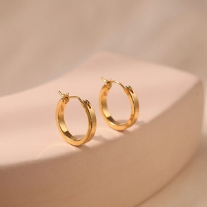 Detailed close-up of polished 18K gold plated brass hoop earrings with minimalist design