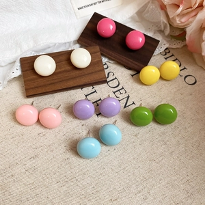 Macro detail of seven candy-colored dome stud earrings on a vintage display