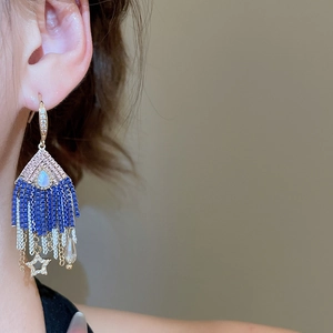 Detailed close-up of crystal tassel earrings with blue beads and star pendant details