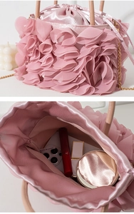 Detail of pink pleated satin evening bag with drawstring closure and metal chain strap
