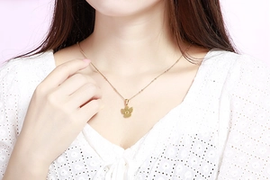 Dettaglio della collana con ciondolo a fiore dorato e lettera O incisa su una modella