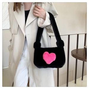 Detail of soft black plush shoulder bag featuring a cute pink 3D heart and fuzzy texture