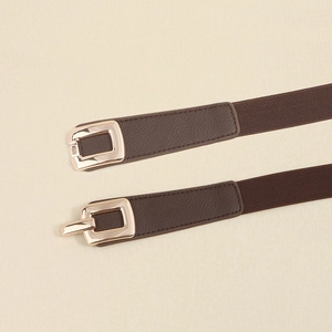 Close-up of brown elastic dress belt featuring a polished gold rectangular metal buckle