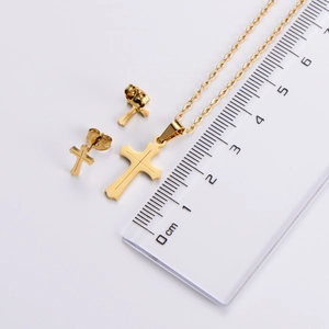 Macro view of gold cross earrings and pendant set next to a ruler for size reference