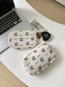 Close-up of rectangular cherry print fabric organizers with Les grenades text on desk