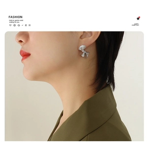 Close-up of model wearing irregular textured silver fan-shaped earrings in french style