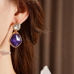 Gros plan de boucles d'oreilles vintage en or avec cristal violet sur le mannequin