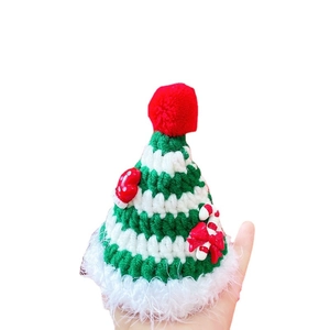 Green and white knitted pet Christmas hat with red pompom and festive star ornaments