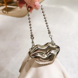 Sliver lip-shaped metal evening bag with bead chain handle shown held by hand
