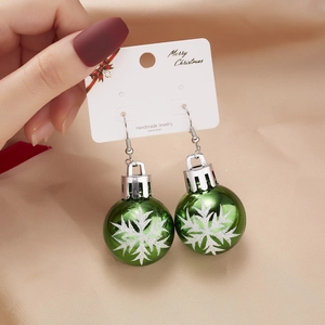 Close-up of festive green Christmas ball earrings with white snowflake patterns