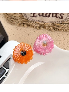 Detail of pink and orange acetate daisy hair claws on a white ceramic tray