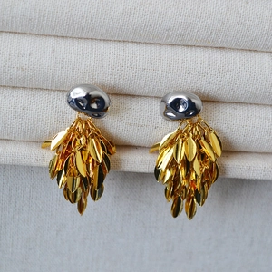 Detailed shot of two-tone leaf tassel earrings featuring gold and silver metal textures