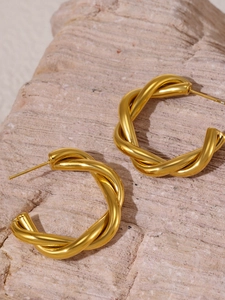 Detailed close-up of gold-plated twisted geometric C-shape earrings on natural stone