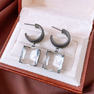 Detail of square glass drop earring in gunmetal C-shape hook within a vintage jewelry box
