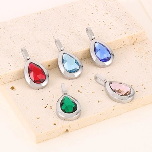 Five teardrop-shaped crystal pendants in various colors on a natural stone background