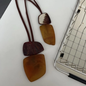 Bohemian brown resin geometric pendant necklace with dark suede cord on white surface