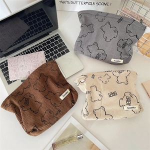 Detailed view of three corduroy makeup bags with cute bear prints in a desk setting