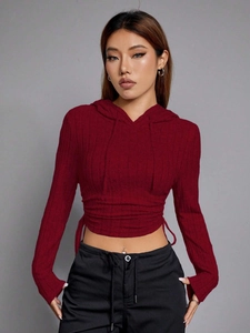 Detail of burgundy ribbed knit crop top featuring long sleeves and drawstring waist