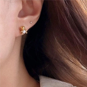 Close-up of golden bear earring with pearl inlay worn on ear for a dainty look