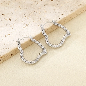 Macro shot of twisted silver stainless steel hoop earrings on stone background