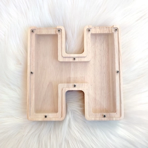 Letter H shaped oak wood piggy bank with clear acrylic panel on white plush background