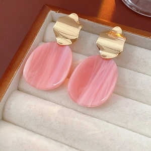 Détail de la boucle d'oreille ovale en acrylique rose marbré avec métal doré irrégulier