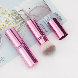 Detail of pink retractable makeup brush showing closed and open states with synthetic bristles