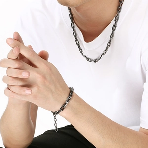 Detail of dark gray titanium cross chain necklace and bracelet set worn by a model