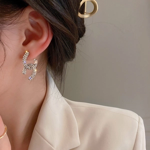 Close-up of sparkling rhinestone-encrusted double C stud earrings on model's ear