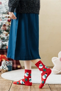Detail der roten Weihnachts-Baumwollsocken mit festlichen Schneemann- und Baum-Mustern am Modell