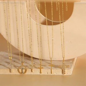 Six 14K gold plated cross necklaces with sparkling zircon pendants on stone display