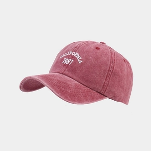 Detail of washed red baseball cap with white California 1987 embroidery and vintage texture